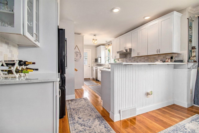 kitchen with white cabinets, decorative backsplash, light wood-type flooring, and sink