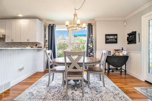 dining space featuring hardwood / wood-style flooring, an inviting chandelier, and ornamental molding