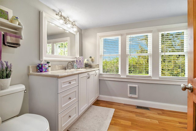 bathroom with hardwood / wood-style floors, vanity, a healthy amount of sunlight, and toilet