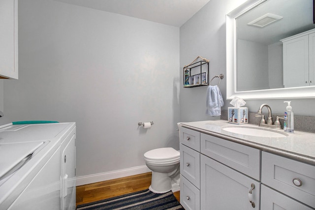 bathroom featuring hardwood / wood-style flooring, vanity, toilet, and washing machine and clothes dryer