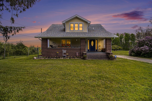 view of front of property with covered porch and a lawn