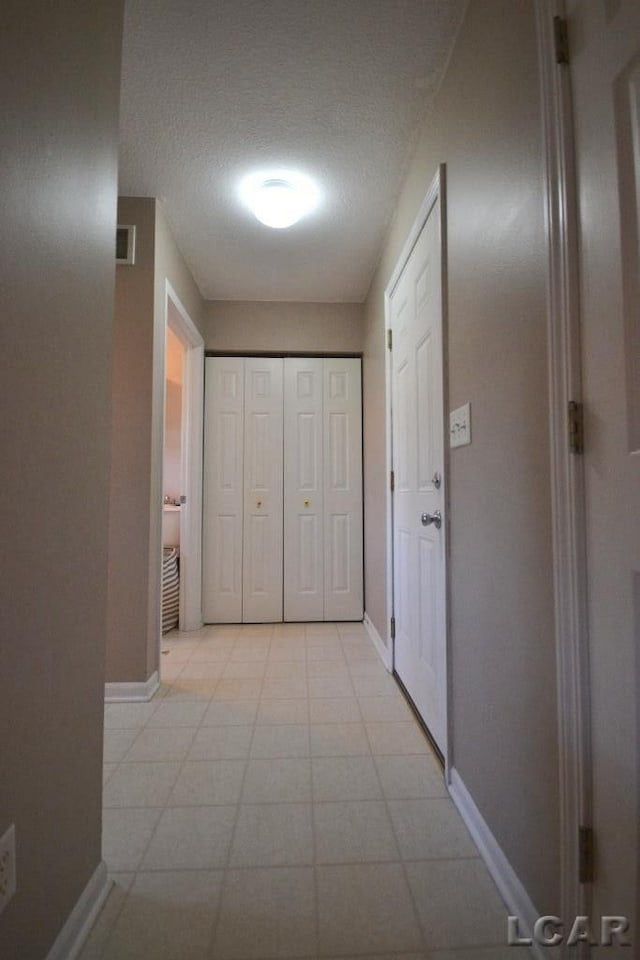 hallway with light tile patterned floors and a textured ceiling