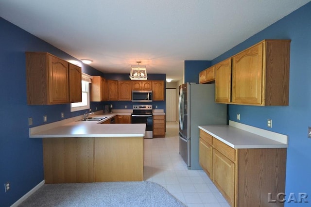 kitchen featuring kitchen peninsula, appliances with stainless steel finishes, pendant lighting, and sink