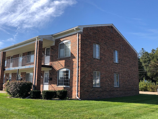 view of property exterior with a balcony and a lawn