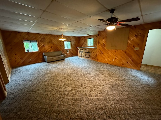 additional living space featuring wooden walls, carpet floors, and ceiling fan