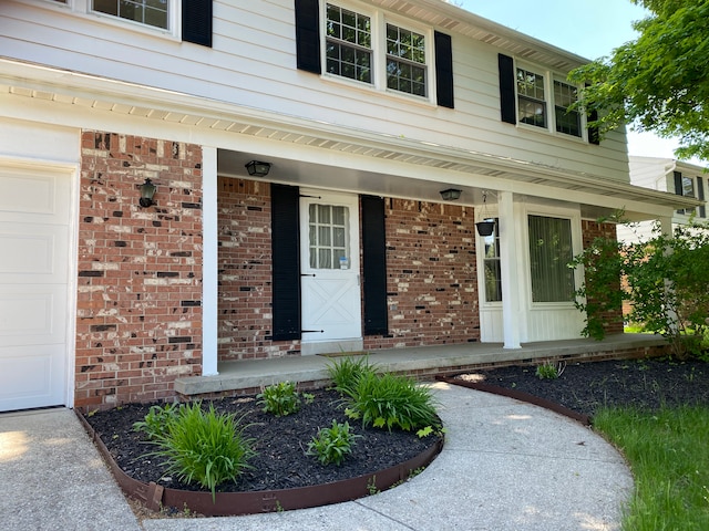 view of exterior entry featuring a porch and a garage