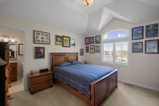 carpeted bedroom with vaulted ceiling and ensuite bath