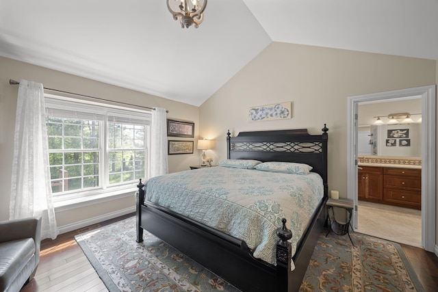 bedroom with lofted ceiling, wood-type flooring, and ensuite bath