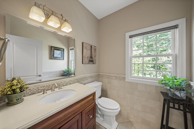 bathroom featuring toilet, vanity, tile patterned floors, and tile walls