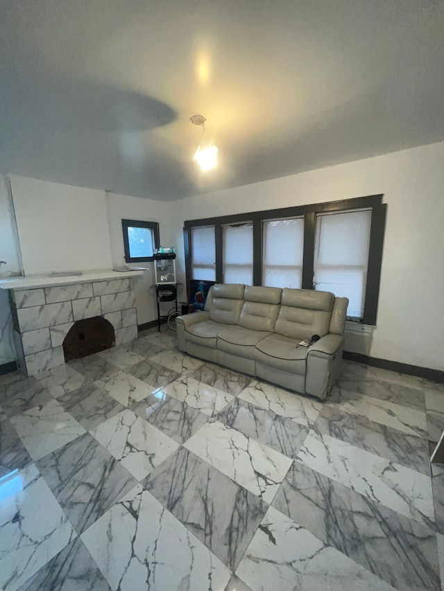 unfurnished living room featuring marble finish floor and baseboards