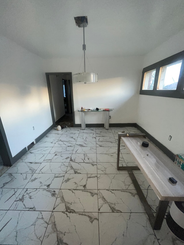 unfurnished dining area featuring marble finish floor and baseboards