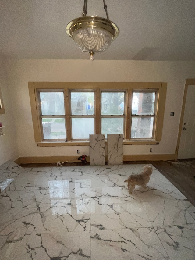 interior space featuring a healthy amount of sunlight, marble finish floor, and baseboards