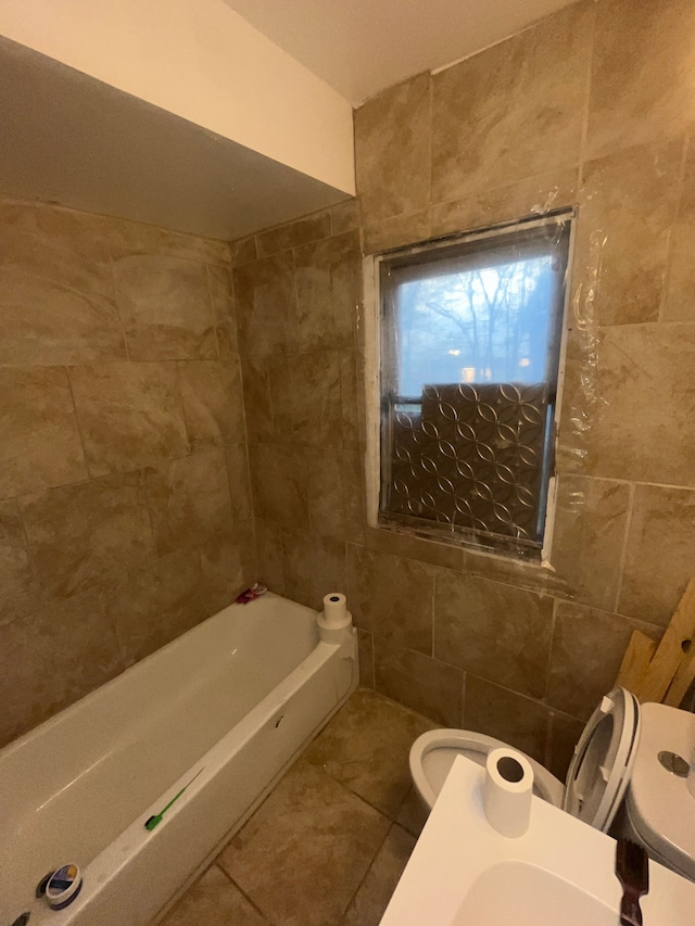 bathroom featuring tile patterned flooring, a bathing tub, tile walls, and toilet