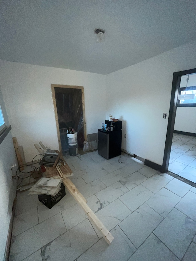 empty room featuring marble finish floor and baseboards