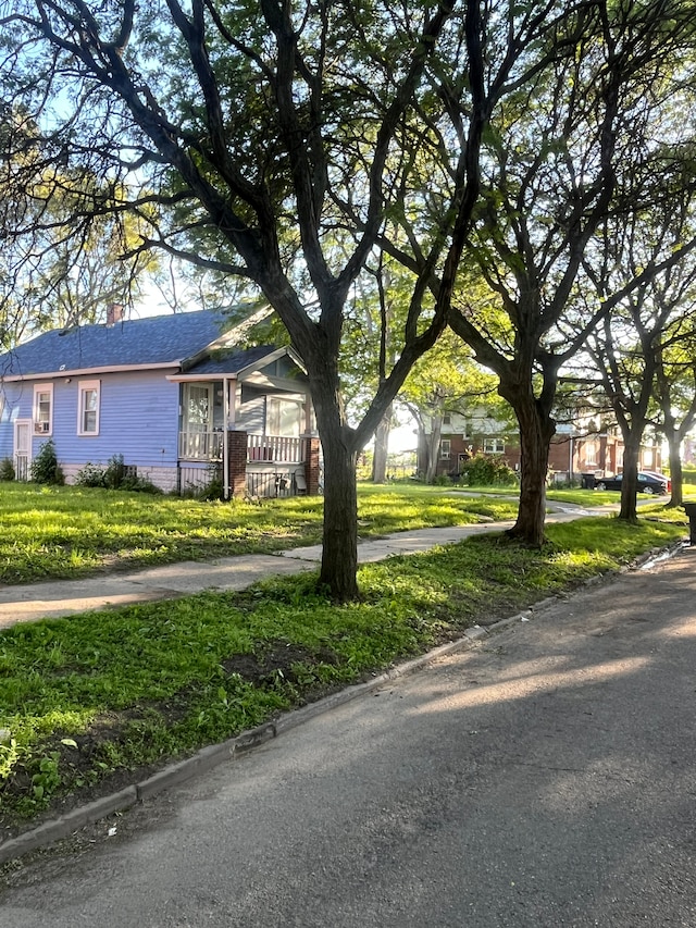 view of front of house featuring a shingled roof, a chimney, a front lawn, and a porch