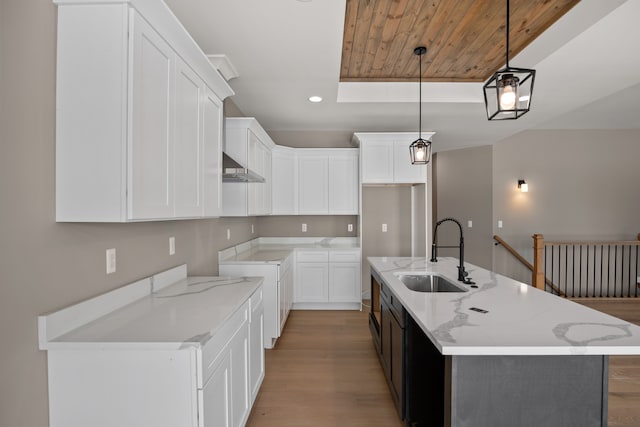 kitchen featuring hanging light fixtures, sink, an island with sink, and white cabinets