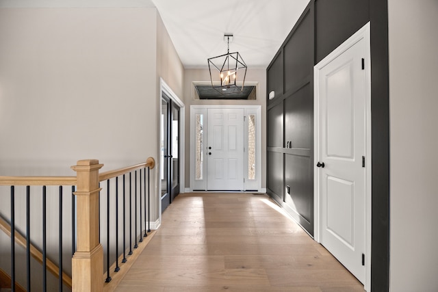 doorway with an inviting chandelier and light hardwood / wood-style flooring