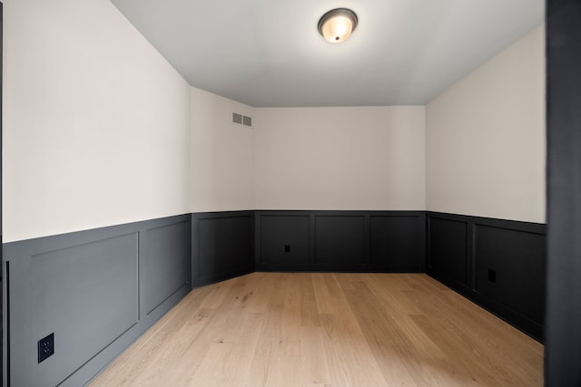 35873 Glenville Dr, New Baltimore, MI 48047 - empty room with a decorative wall, visible vents, a wainscoted wall, and light wood finished floors