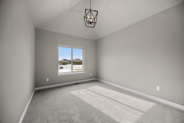 carpeted spare room featuring an inviting chandelier and lofted ceiling