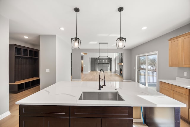 kitchen featuring sink, light stone counters, light wood-type flooring, light brown cabinets, and a kitchen island with sink