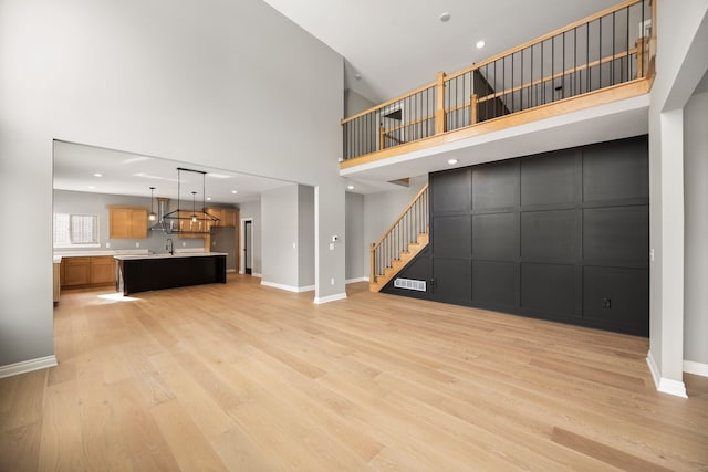 unfurnished living room featuring a towering ceiling and light hardwood / wood-style flooring