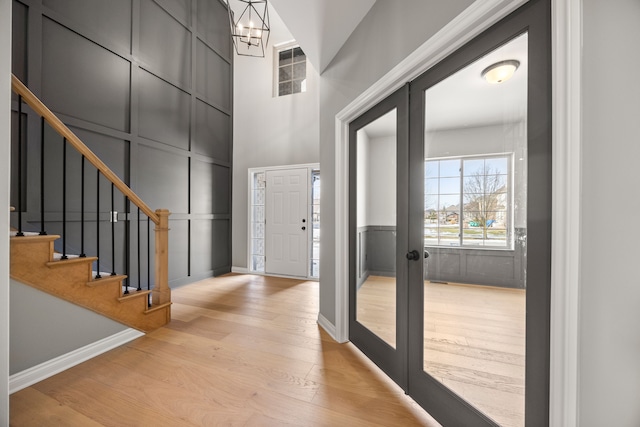 entryway featuring french doors, a high ceiling, light hardwood / wood-style flooring, and a notable chandelier