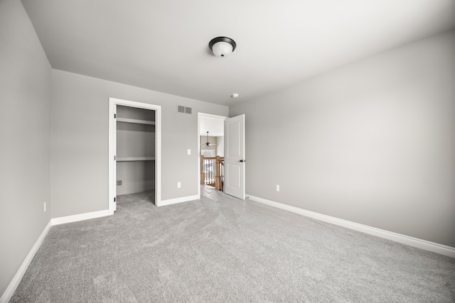 unfurnished bedroom featuring light carpet, a spacious closet, and a closet