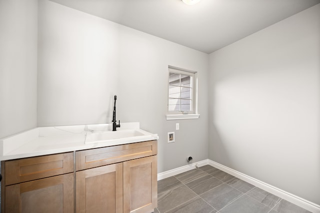 laundry room featuring electric dryer hookup, sink, hookup for a washing machine, and cabinets