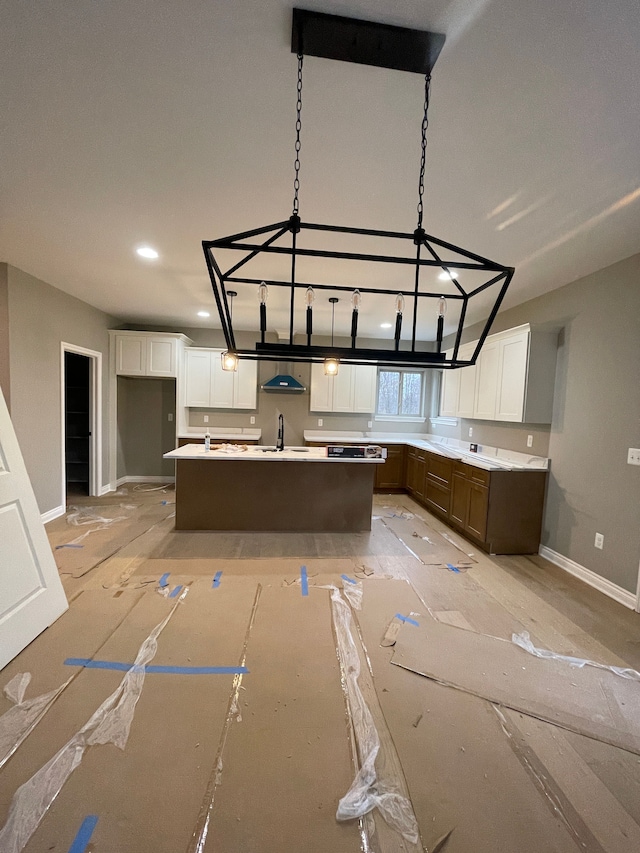 kitchen with white cabinets, pendant lighting, sink, and a kitchen island with sink