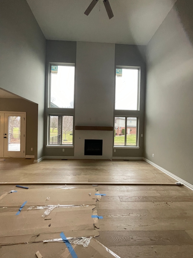 unfurnished living room with light wood-type flooring, a wealth of natural light, and ceiling fan