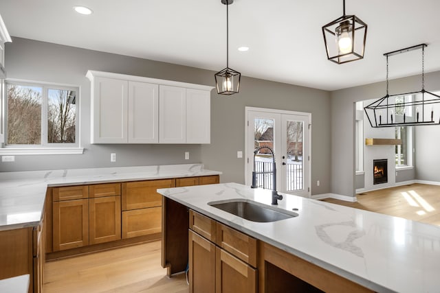 kitchen featuring light hardwood / wood-style flooring, decorative light fixtures, a fireplace, and french doors