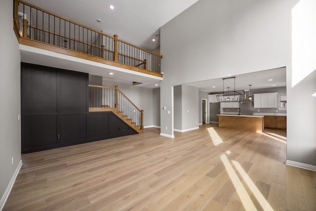 unfurnished living room featuring light hardwood / wood-style floors and a high ceiling