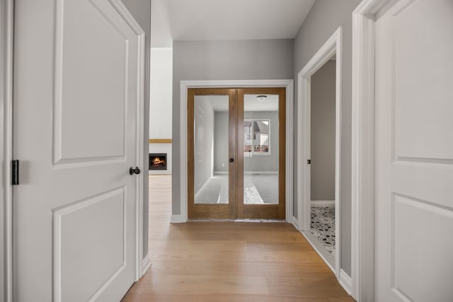 hallway with light wood-type flooring and french doors