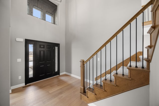 entryway featuring a towering ceiling and light hardwood / wood-style flooring