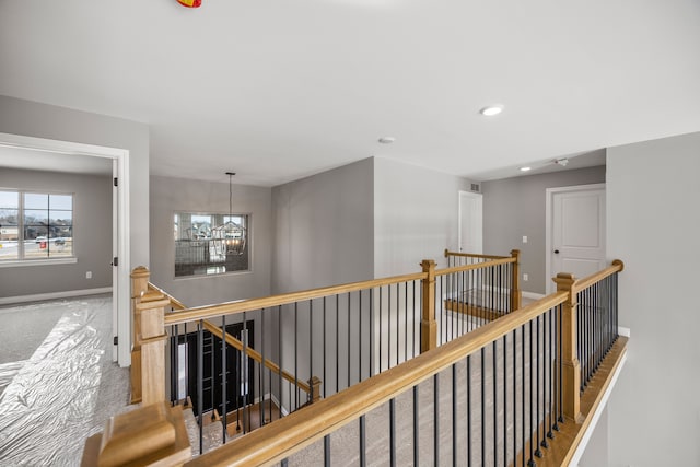 hall featuring carpet floors and a notable chandelier