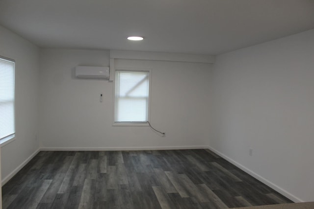 empty room featuring an AC wall unit, a wealth of natural light, and dark hardwood / wood-style floors