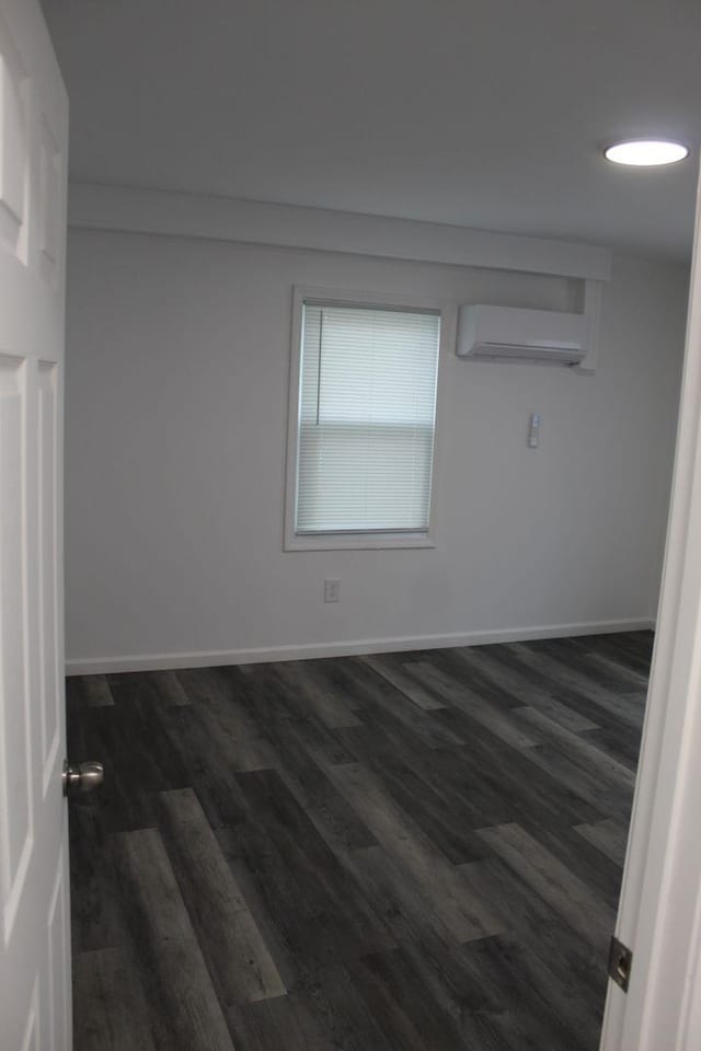 unfurnished room featuring dark hardwood / wood-style flooring and a wall unit AC