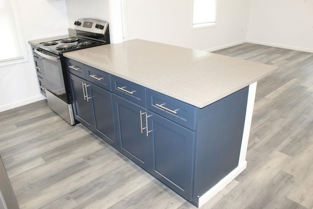 kitchen featuring light wood-type flooring, blue cabinetry, and stainless steel stove