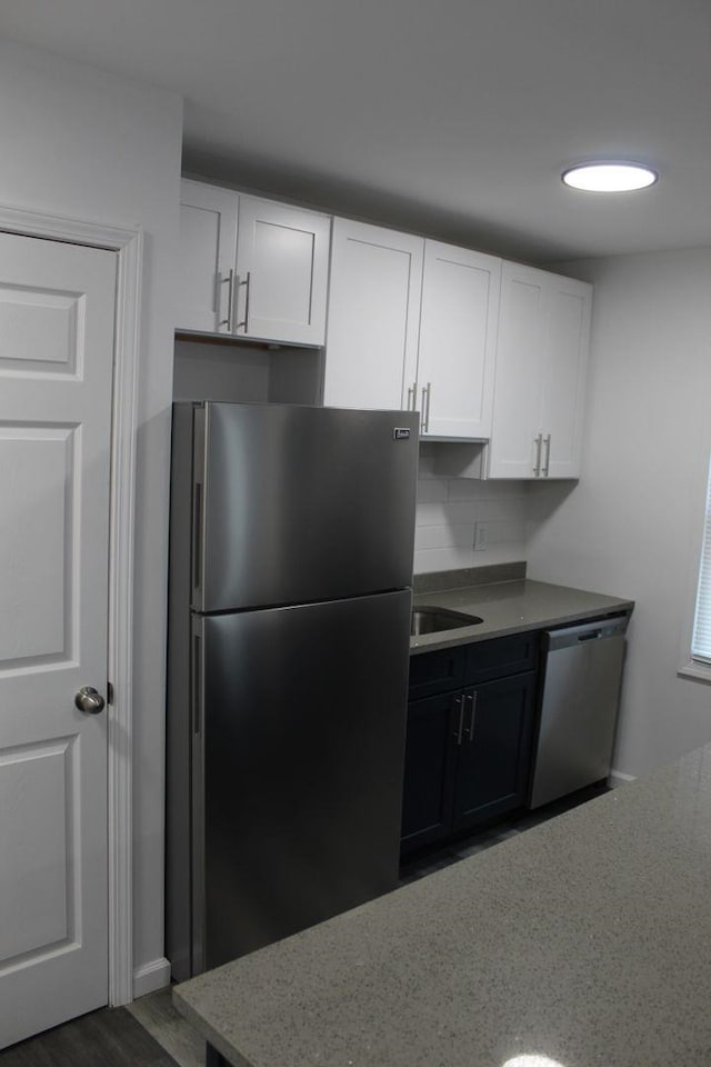 kitchen featuring decorative backsplash, dark wood-type flooring, white cabinets, and stainless steel appliances