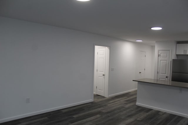 kitchen with white cabinetry, dark wood-type flooring, and fridge