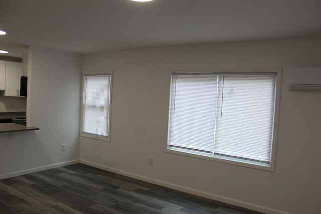 empty room with an AC wall unit and dark wood-type flooring