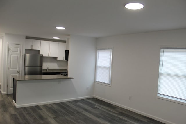 kitchen with white cabinets, kitchen peninsula, stainless steel refrigerator, and a wealth of natural light