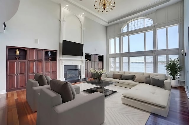 living room featuring a towering ceiling, dark wood-type flooring, and a chandelier