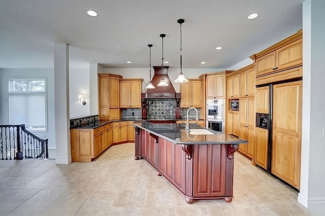 kitchen featuring custom exhaust hood, a breakfast bar, a kitchen island with sink, sink, and decorative light fixtures