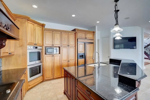 kitchen featuring sink, built in appliances, decorative light fixtures, a center island with sink, and dark stone countertops