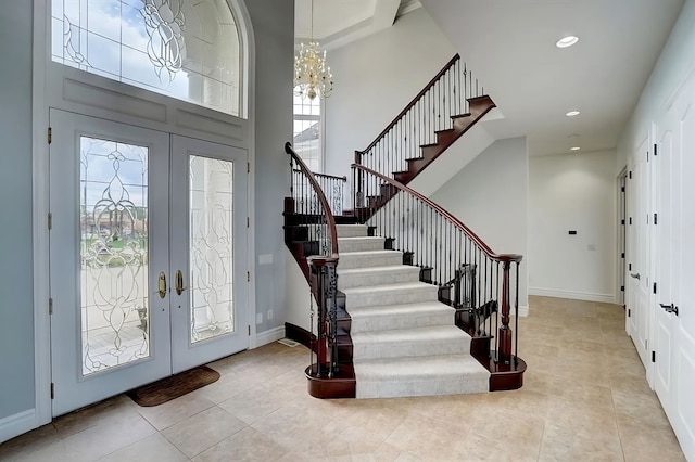 foyer with french doors, light tile patterned floors, an inviting chandelier, and a wealth of natural light