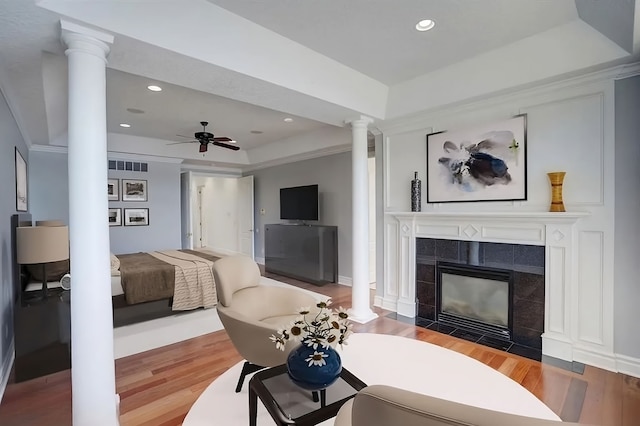 living room featuring hardwood / wood-style floors, a raised ceiling, and a tiled fireplace