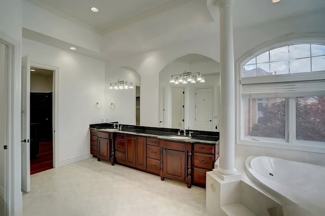 bathroom featuring vanity, a relaxing tiled tub, and ornate columns