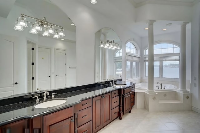 bathroom with tile patterned floors, vanity, a relaxing tiled tub, and ornate columns