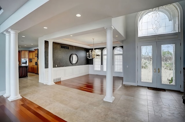 foyer entrance with french doors, light hardwood / wood-style flooring, and a chandelier